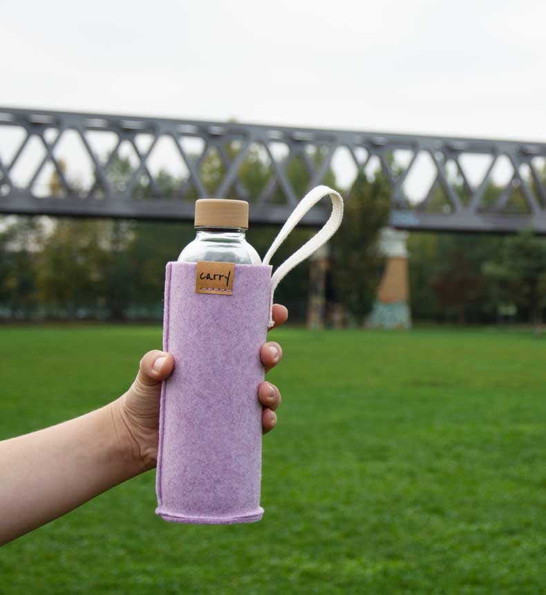 Rosa Filzhülle mit Trinkflasche vor grüner Wiese