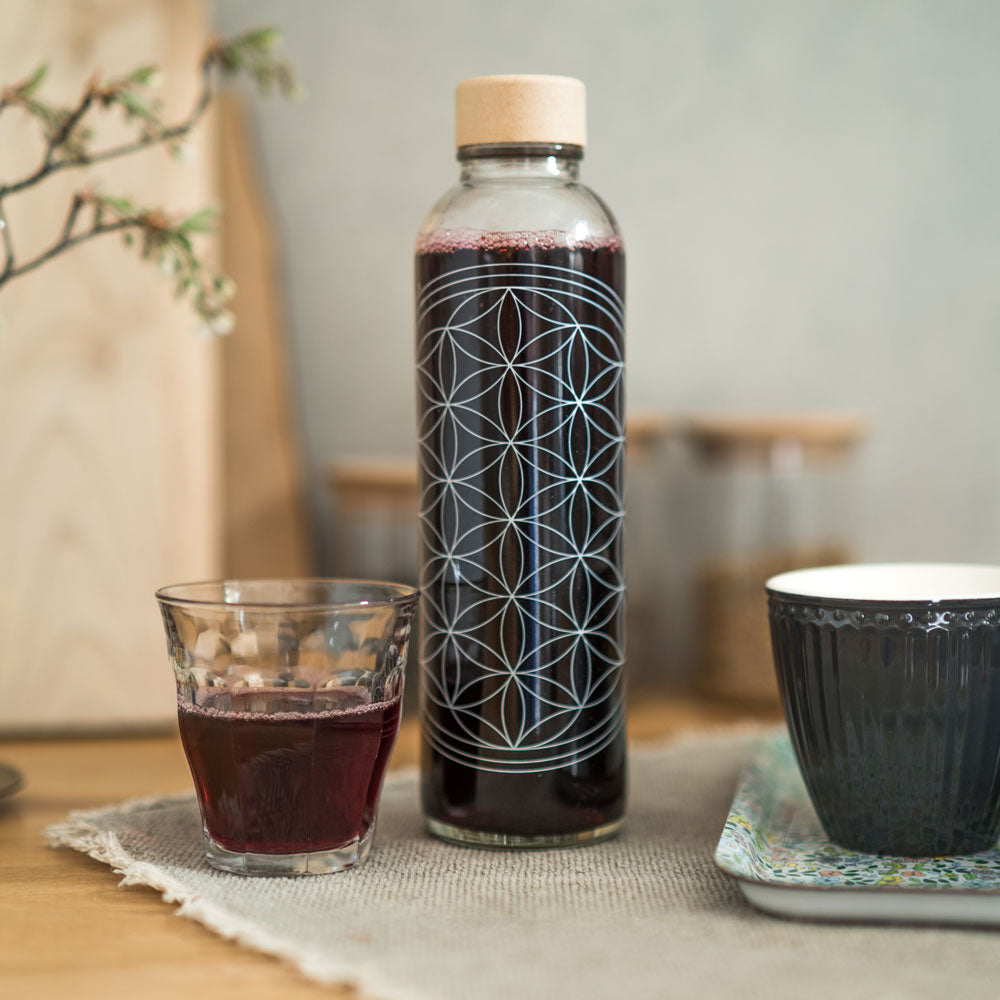 Glastrinkflasche mit Blume des Lebens gefüllt mit rotem Saft