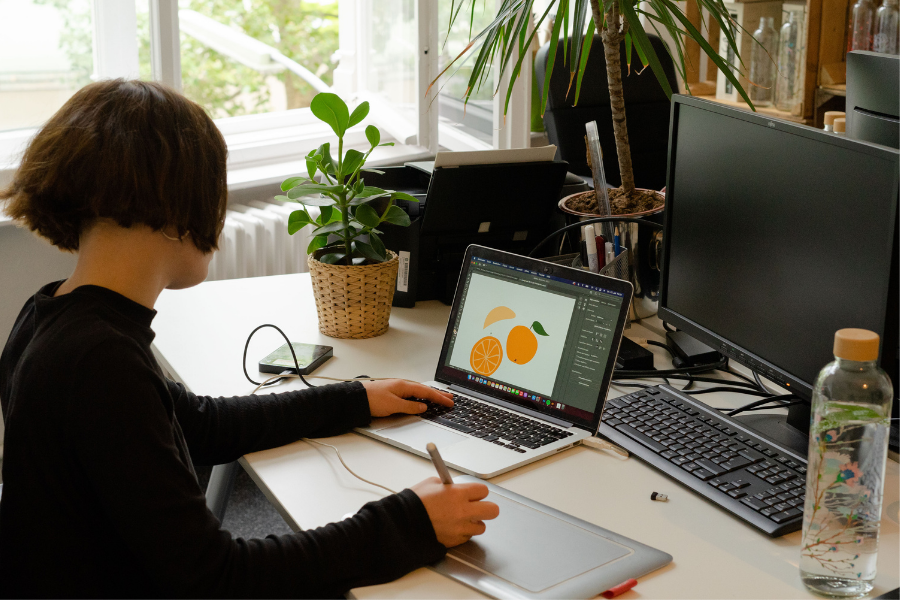 Person sitzt an Schreibtisch mit Laptop