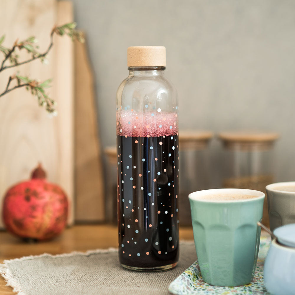 Glastrinkflasche mit bunten Punkten gefüllt mit rotem Saft